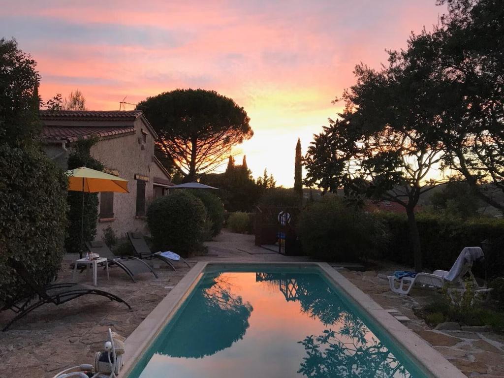 - une piscine dans une cour avec un coucher de soleil en arrière-plan dans l'établissement la beaussetane, au Beausset
