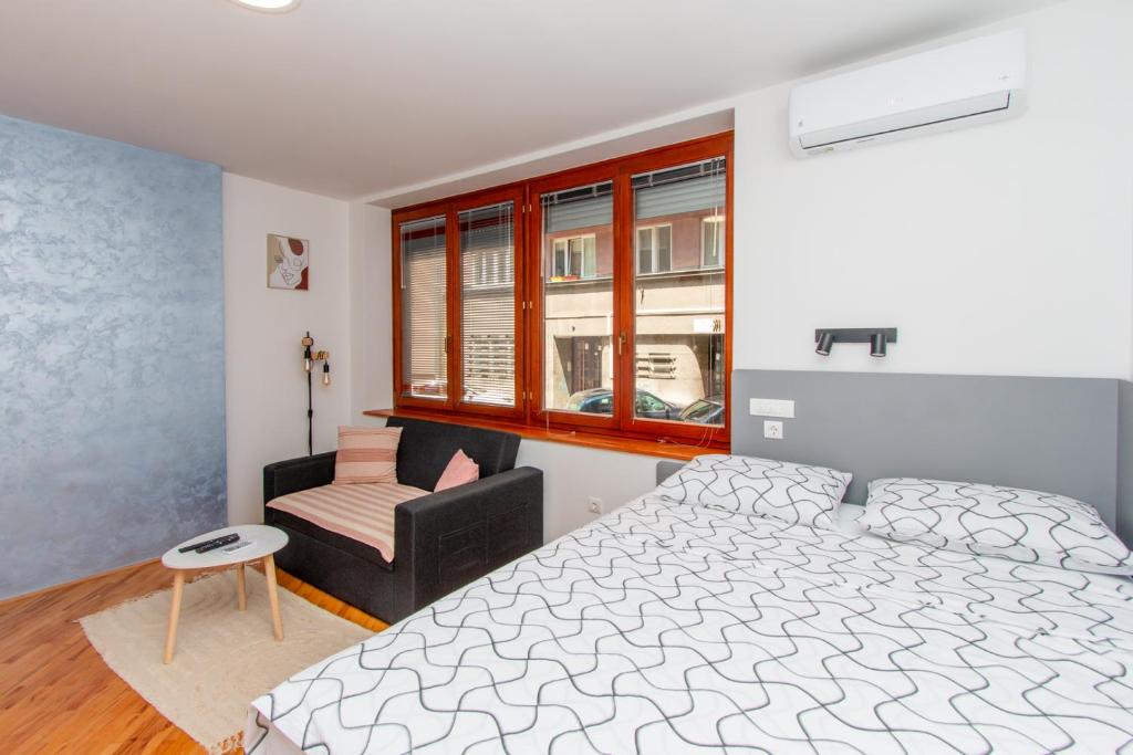 萨拉热窝Apartman Bene的一间卧室，里面有一张床、一把椅子和一扇窗户。