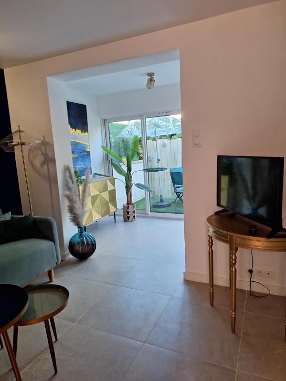 un salon avec une télévision et une table dans l'établissement Mimilou Agathines, au Cap d'Agde