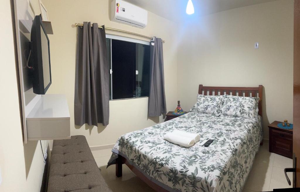 a small bedroom with a bed and a television at Casa da Pri in Rio das Ostras