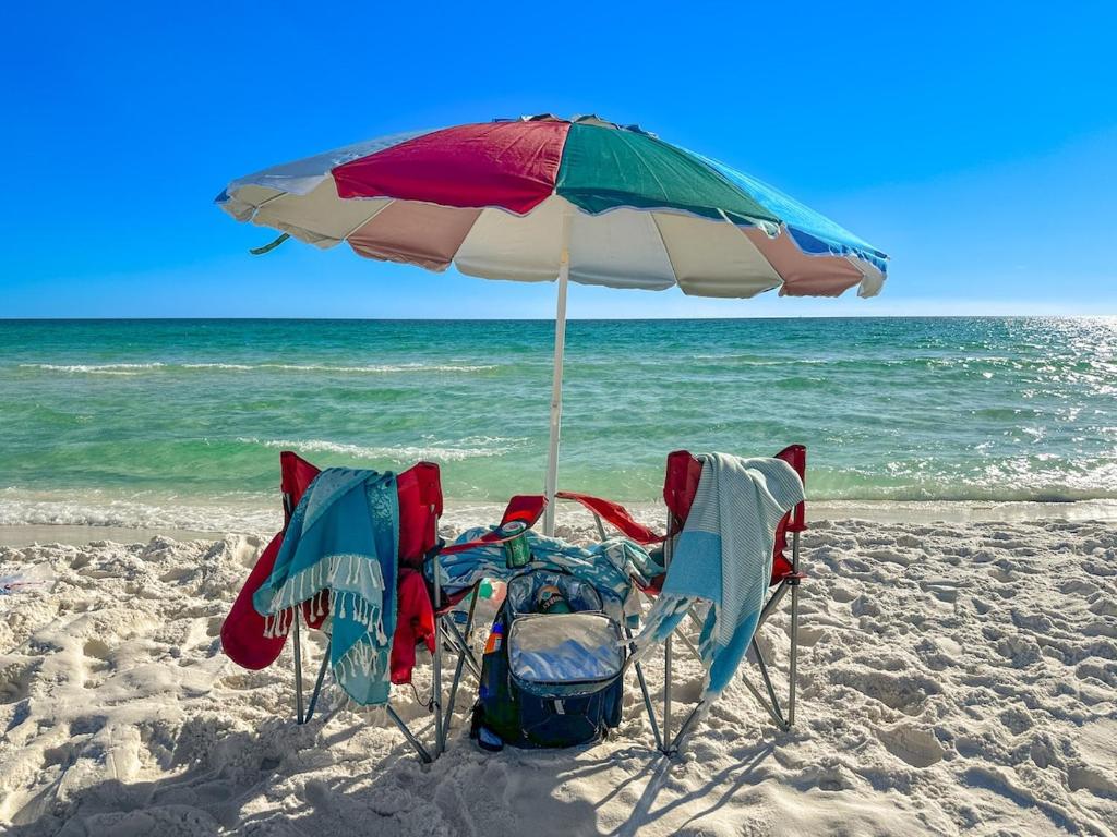 two chairs under an umbrella on the beach at Sunrise Destin-ation Beach view Heated Pool in Destin