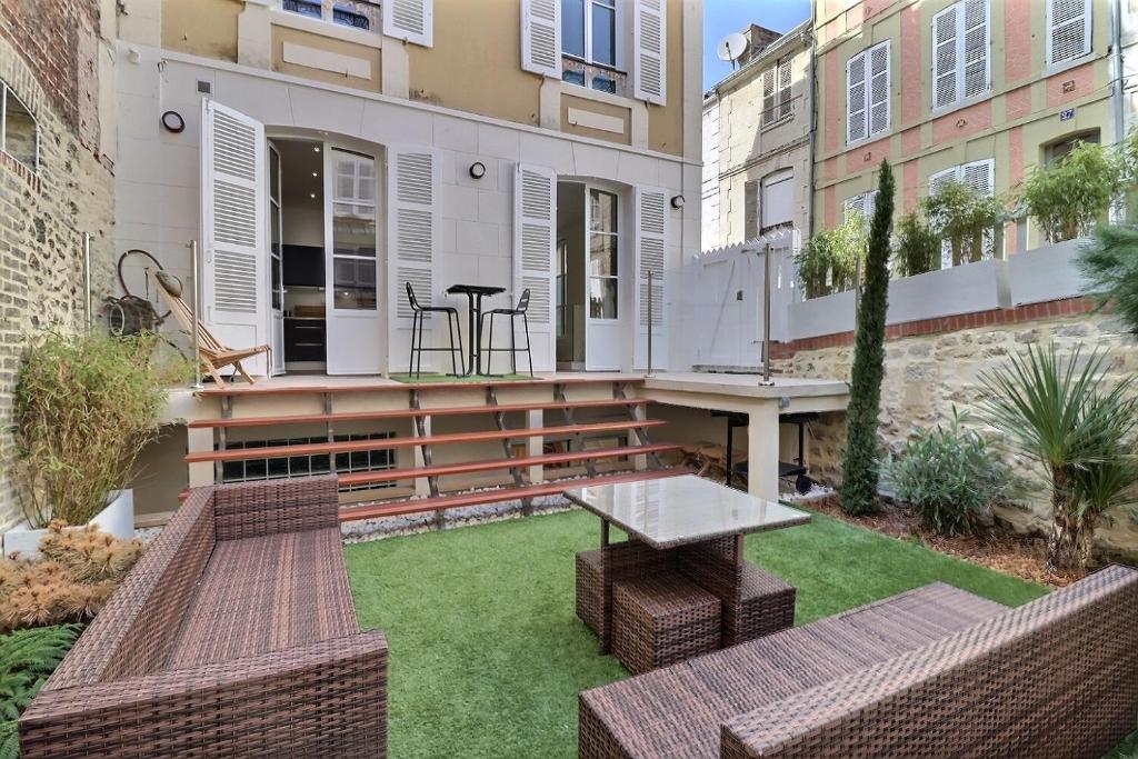 un patio avec deux bancs et une table dans l'établissement Havre de paix & Jardin Quartier Bonsecours Fibré, à Trouville-sur-Mer