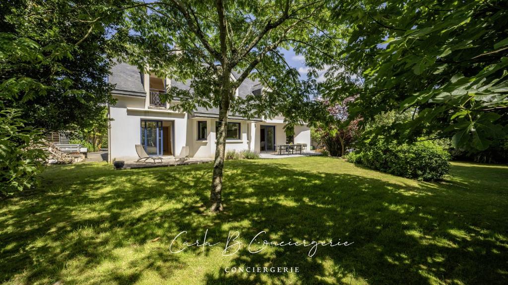 une maison blanche avec un arbre dans la cour dans l'établissement LA ROSE DES VENTS - CONCARNEAU - 8 personnes, à Concarneau