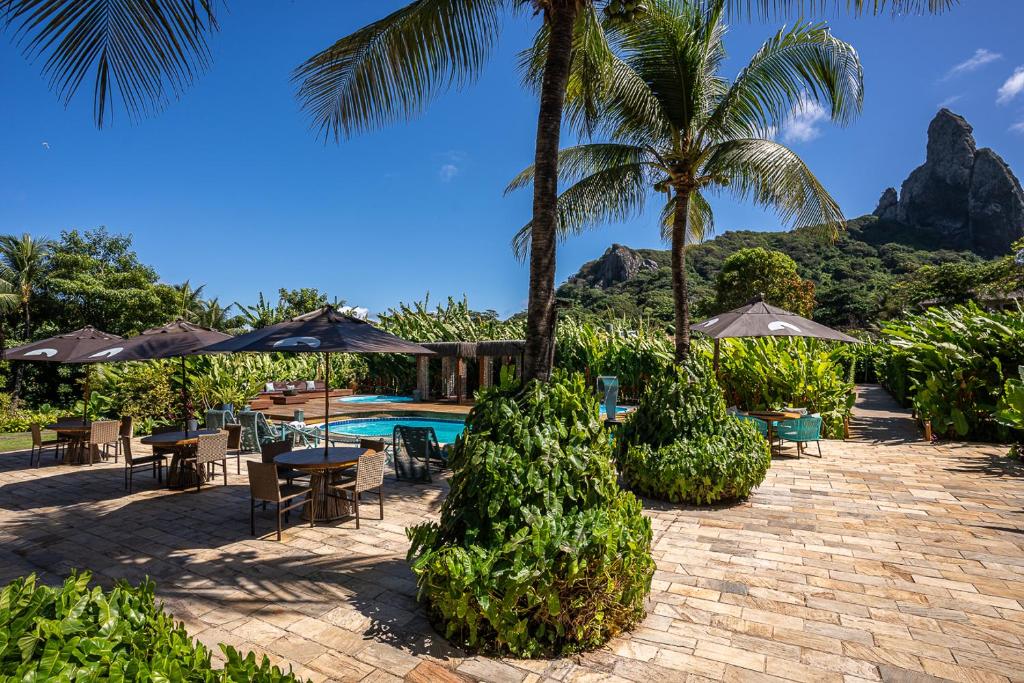 a resort with a swimming pool and palm trees and a patio at Dolphin Hotel in Fernando de Noronha