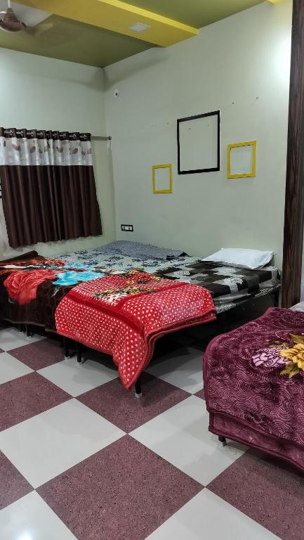een slaapkamer met 2 bedden en een geruite vloer bij Pooja home stay in Ujjain