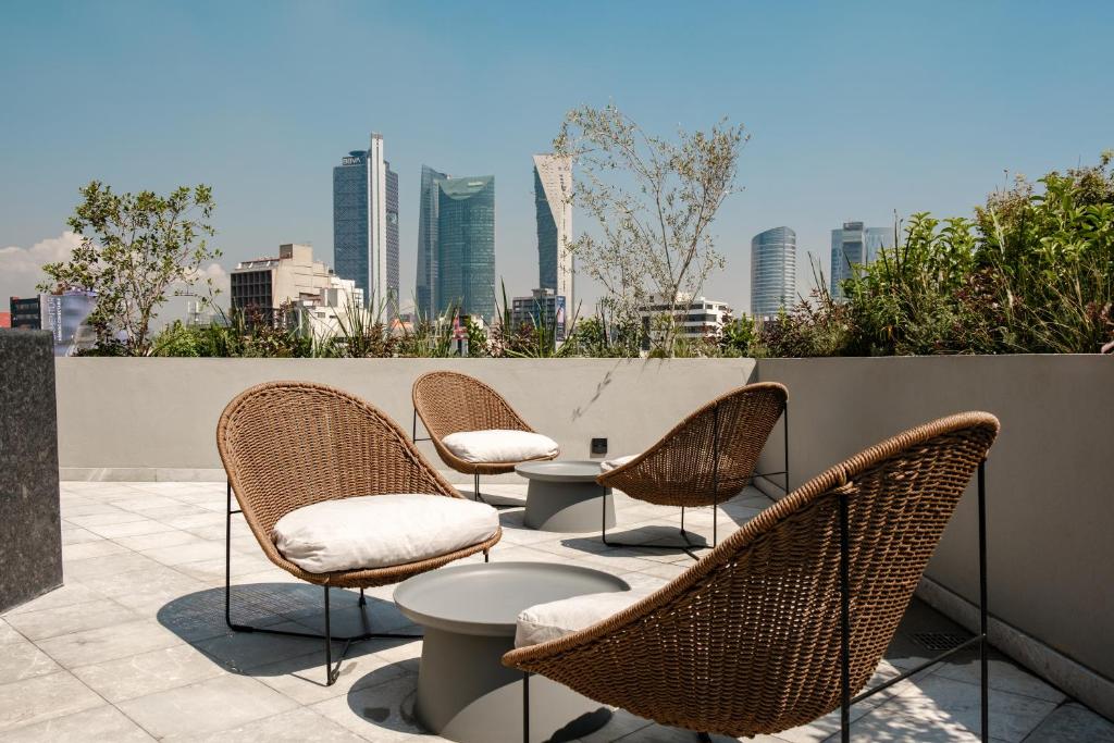 a group of chairs and tables on a patio with a city skyline at Casa Cibeles by Lumina in Mexico City