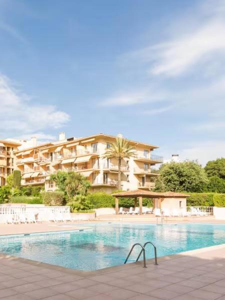 une piscine en face d'un grand bâtiment dans l'établissement Résidence EDEN PARC SAINT TROPEZ 2, à Saint-Tropez
