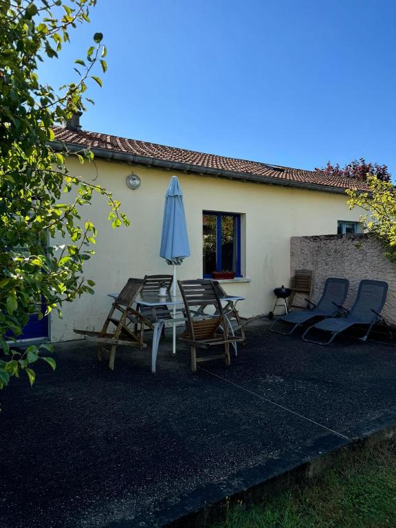 un patio avec une table, un parasol et des chaises dans l'établissement Le petit,gîte à 100m de la plage, à Asnelles