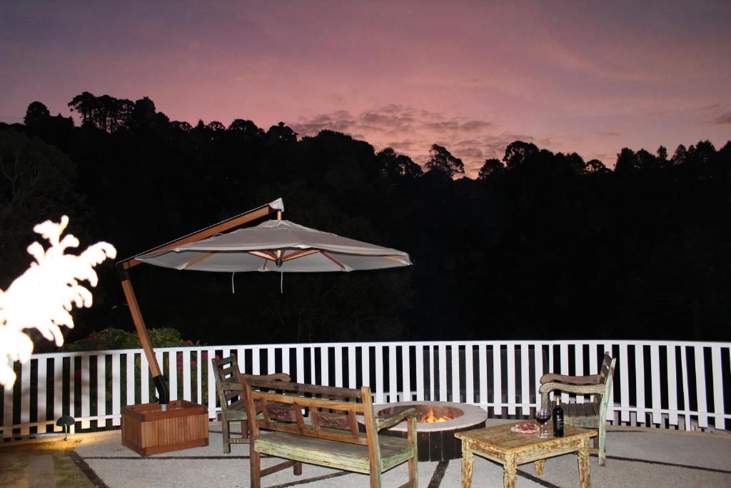 a patio with an umbrella and two chairs and a table at Pousada Grandchamp - Campos do Jordao in Campos do Jordão