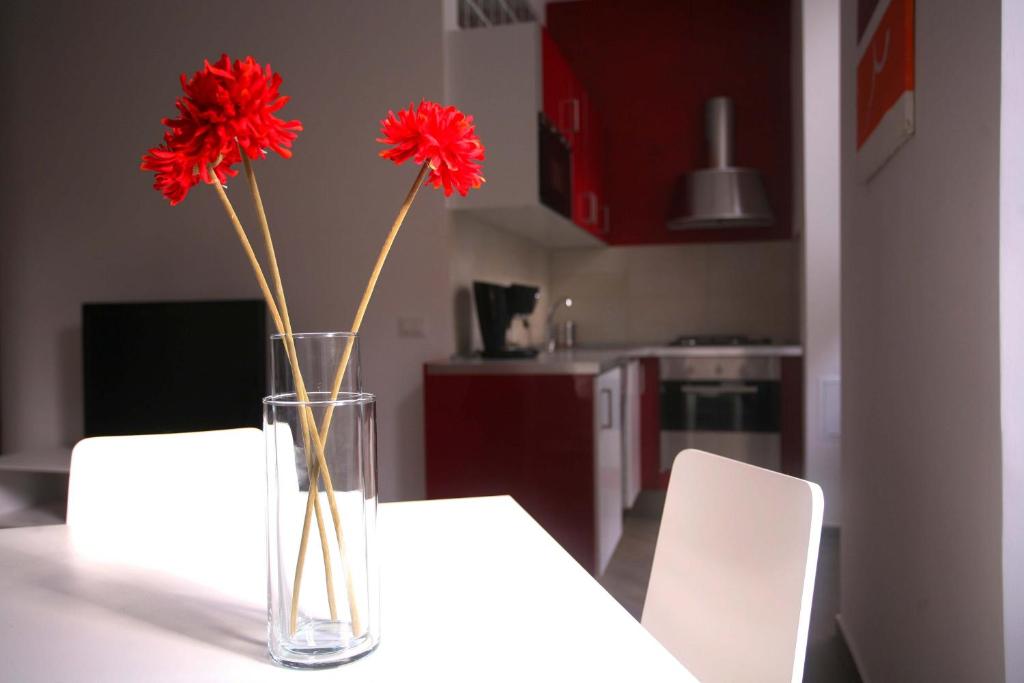 a vase with red flowers sitting on a table at Red Flat In Rome in Rome