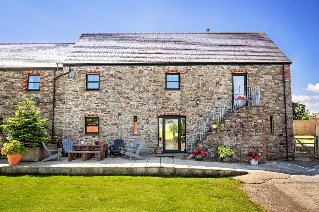 una casa in pietra con un patio di fronte di Kidwelly Farm Cottage a Kidwelly