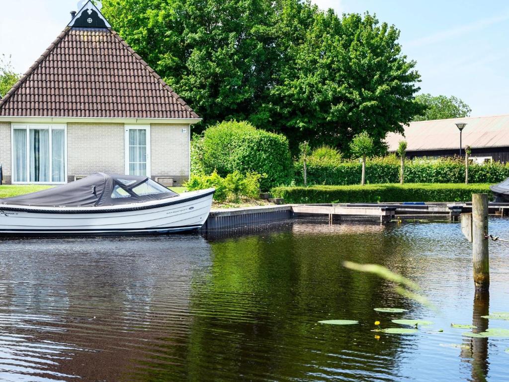 Ein Boot ist im Wasser neben einem Haus angedockt. in der Unterkunft Holiday home with sauna, outdoor spa in Earnewâld