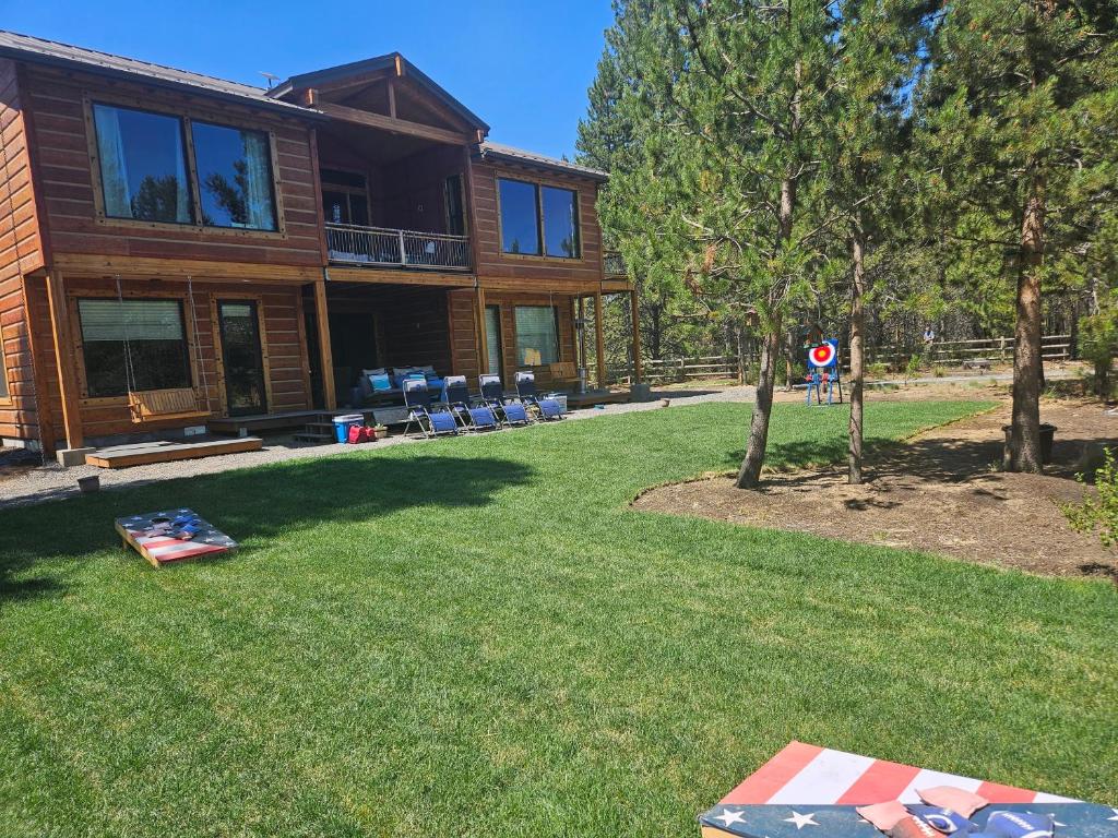 a log cabin with a yard with a house at Beautiful Riverfront Near Mt Bachelor with Hot Tub in Bend