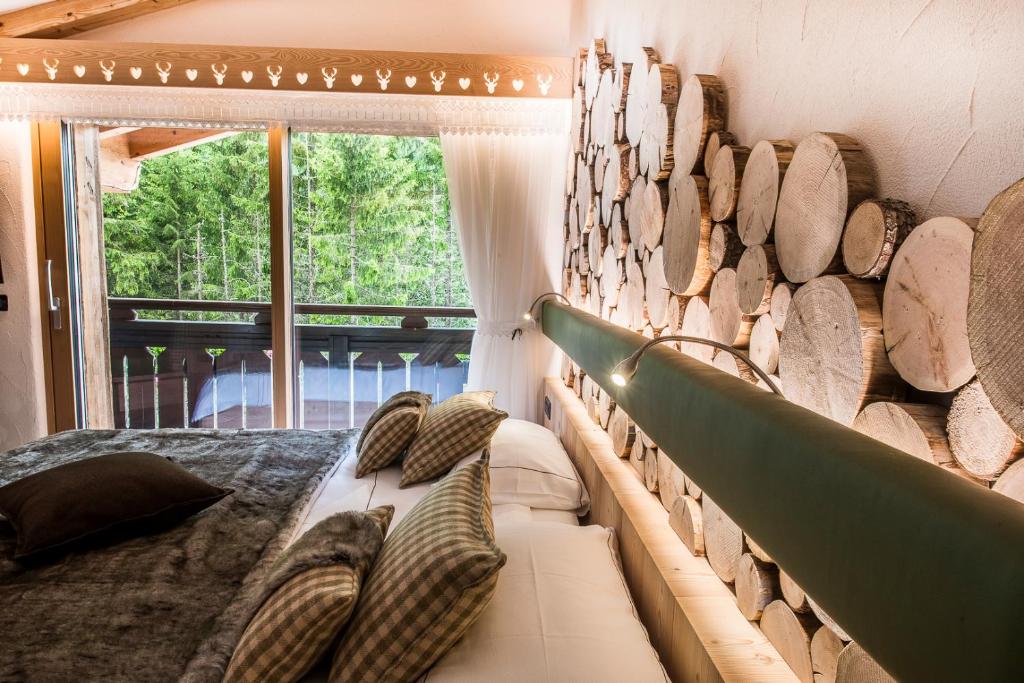 a room with a bed and a wall of logs at Chalet Pineta relax location in Canazei