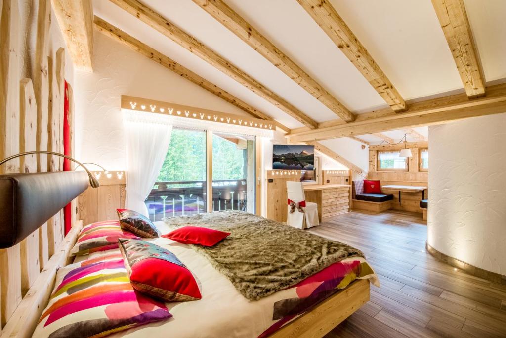 a bedroom with a bed and a large window at Chalet Pineta relax location in Canazei