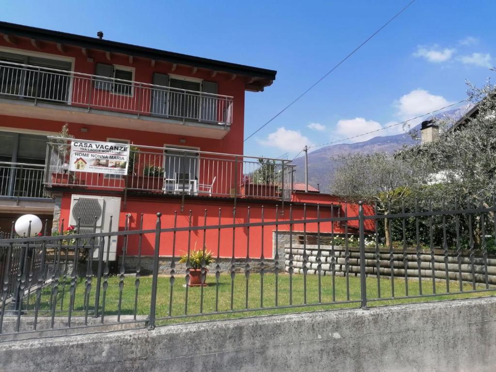 杜比诺Tra lago e montagne home nonna Maria的一座红色的建筑，前面有围栏
