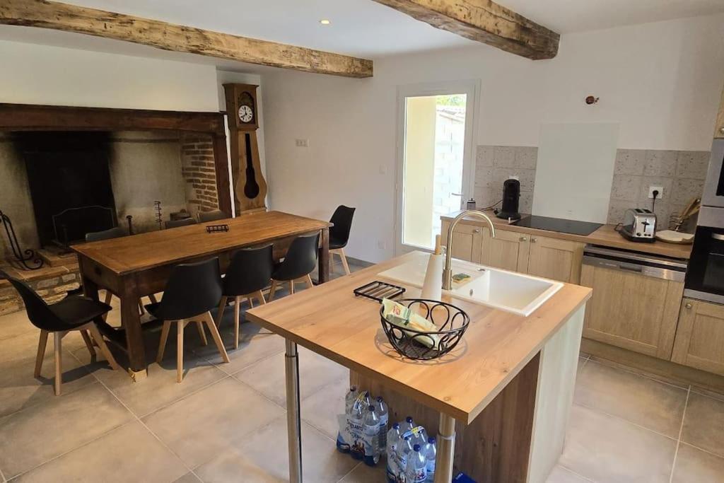 una cucina con tavolo, sedie e lavandino di Aux deux Marronniers Cathares a Castelnau-de-Lévis