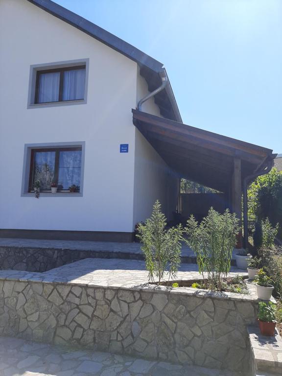 a white house with a stone wall in front of it at Nice view-Plitvice in Korenica