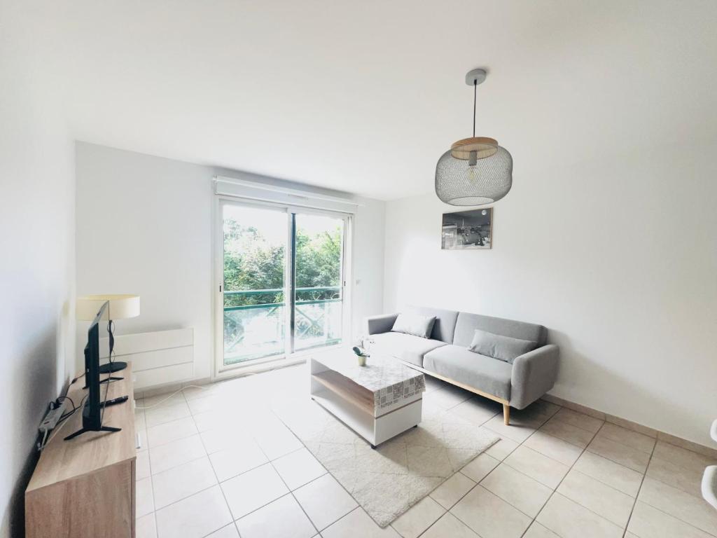 un salon blanc avec un canapé et une table dans l'établissement Appartement des Lilas 25km de Paris et Disney, à Pontault-Combault