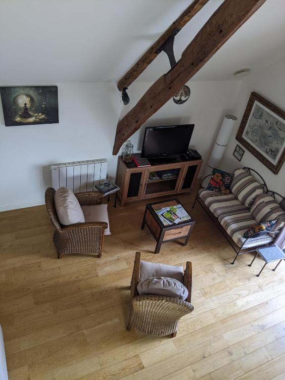 un salon avec des canapés et une télévision à écran plat dans l'établissement Le Nourhoët havre de Paix à l'Orée de Brocéliande, à Campénéac