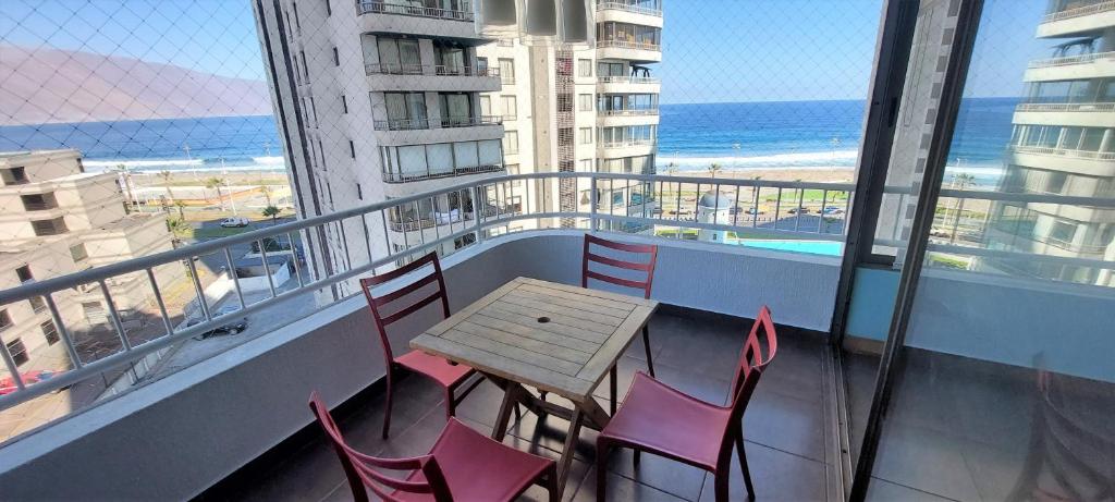 a table and chairs on a balcony with a view of the beach at Departamentos Mar Egeo in Iquique