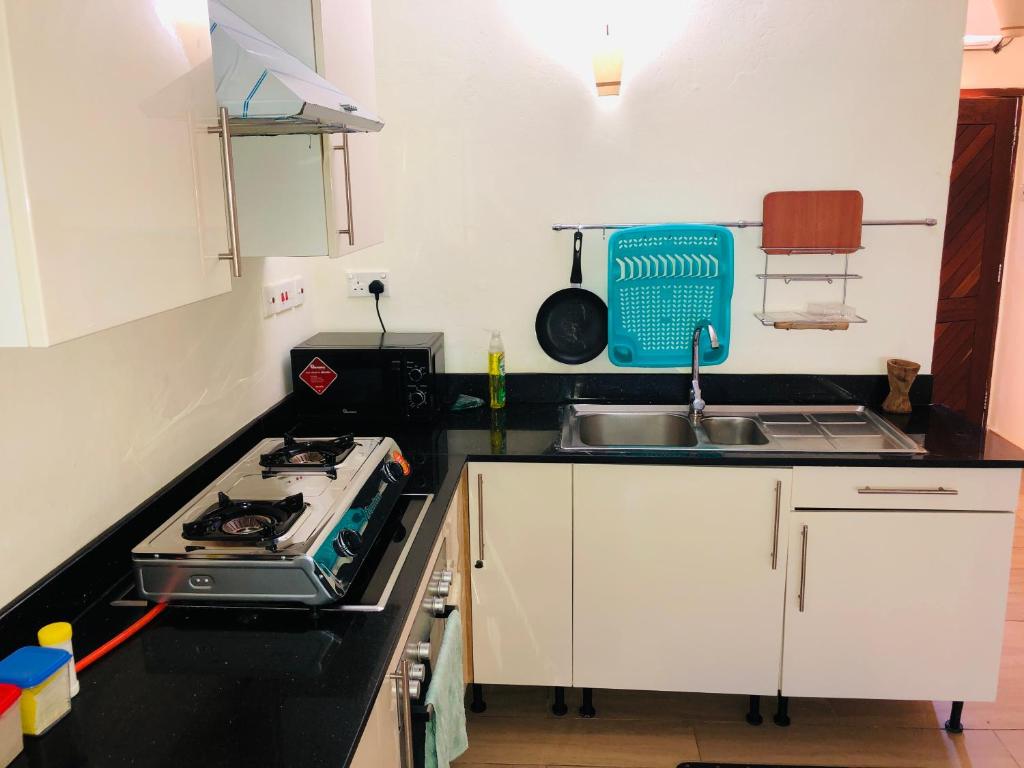 a small kitchen with a stove and a sink at Harmony Homes Beachfront in Diani Beach
