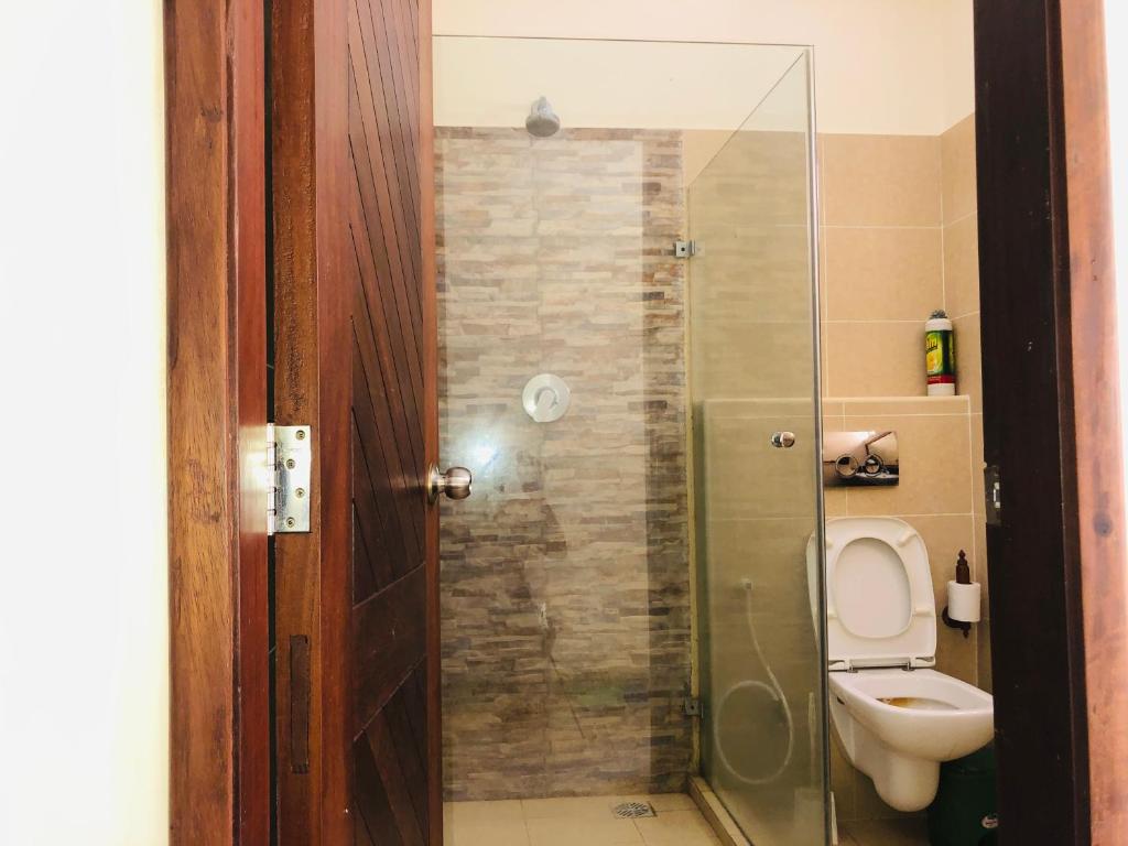 a bathroom with a toilet and a glass shower at Harmony Homes Beachfront in Diani Beach