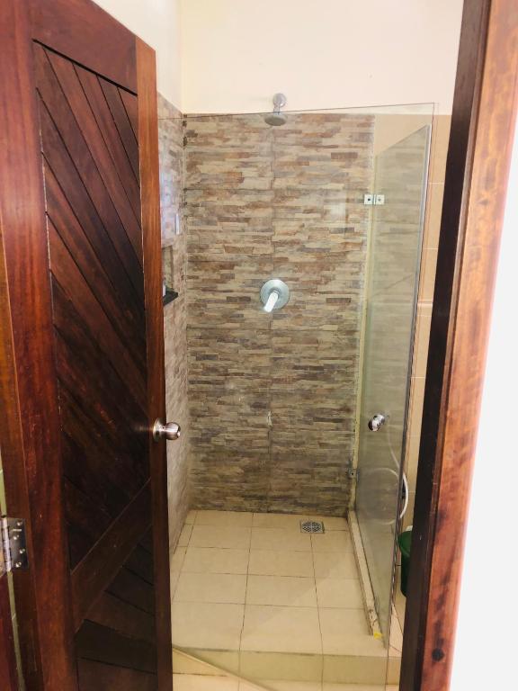 a shower with a glass door in a bathroom at Harmony Homes Beachfront in Diani Beach