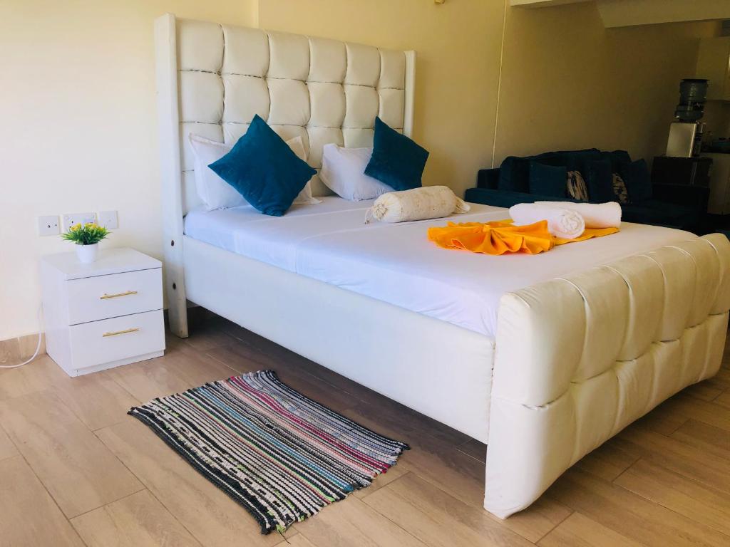 a large white bed in a room with blue pillows at Harmony Homes Beachfront in Diani Beach