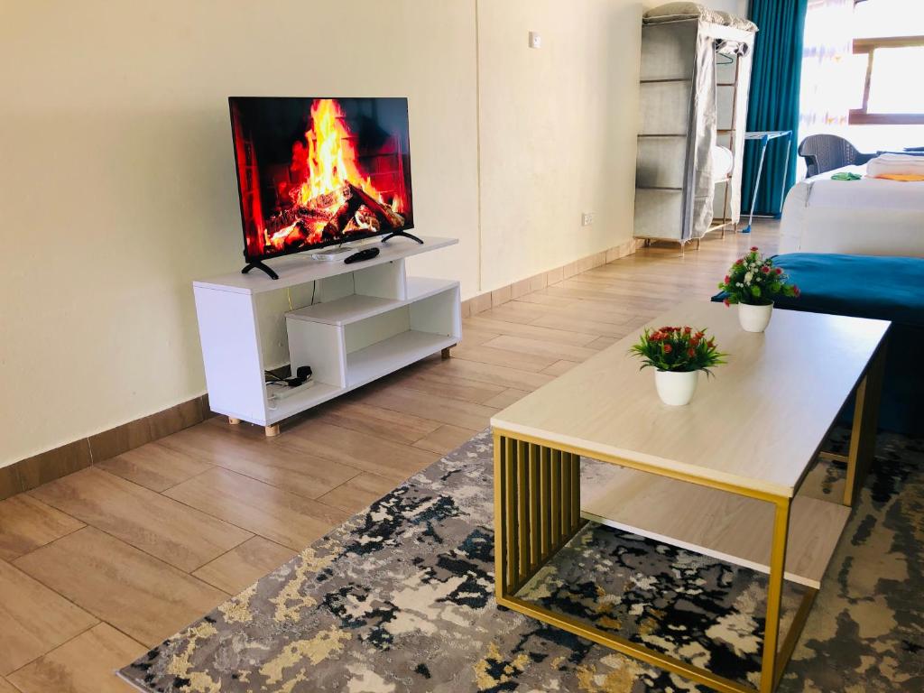 a living room with a tv with a fire on the screen at Harmony Homes Beachfront in Diani Beach