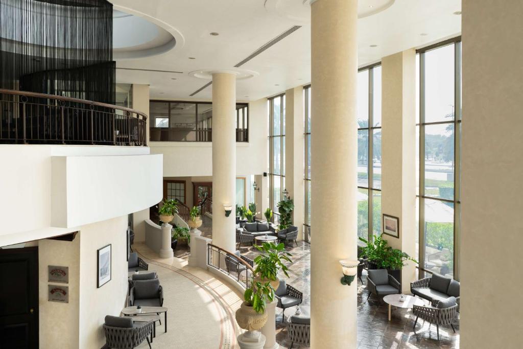 a lobby with chairs and tables and windows at Radisson Blu Hotel & Resort, Abu Dhabi Corniche in Abu Dhabi