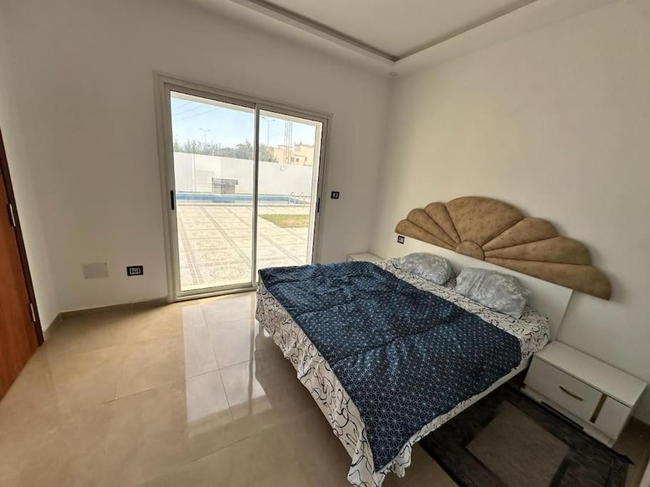 ein Schlafzimmer mit einem Bett und einem großen Fenster in der Unterkunft Villa au cœur de l'île in Taguermess