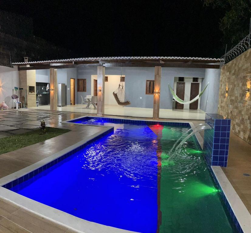 a swimming pool with blue water in front of a house at Casa para aluguel de temporada in Crato