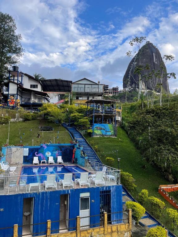 a blue building with chairs on top of a hill at Hotel Campestre el Volcan De Guatape in Guatapé