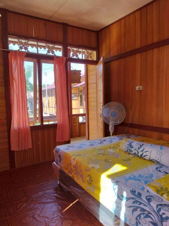 a bedroom with a bed in a room with wooden walls at Bunaken GuestHouse in Bunaken