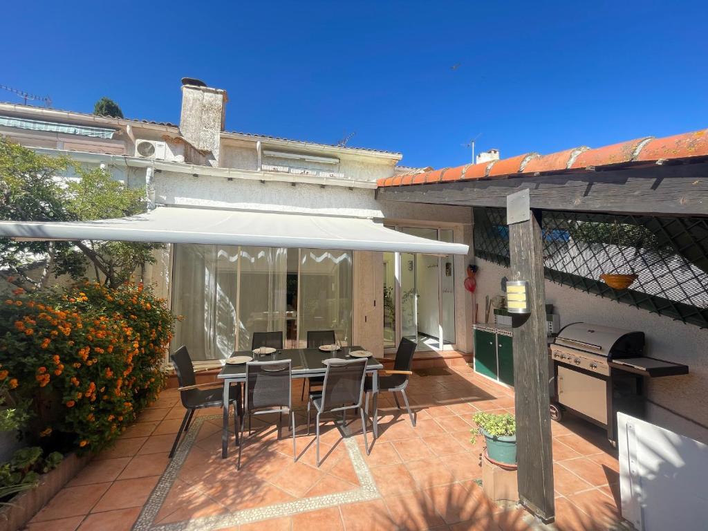 d'une terrasse avec une table et des chaises sous un parasol blanc. dans l'établissement Spacieuse maison 6 pers à Sète - WIFI, animaux bienvenus, parking, clim mobile - FR-1-338-4, à Sète