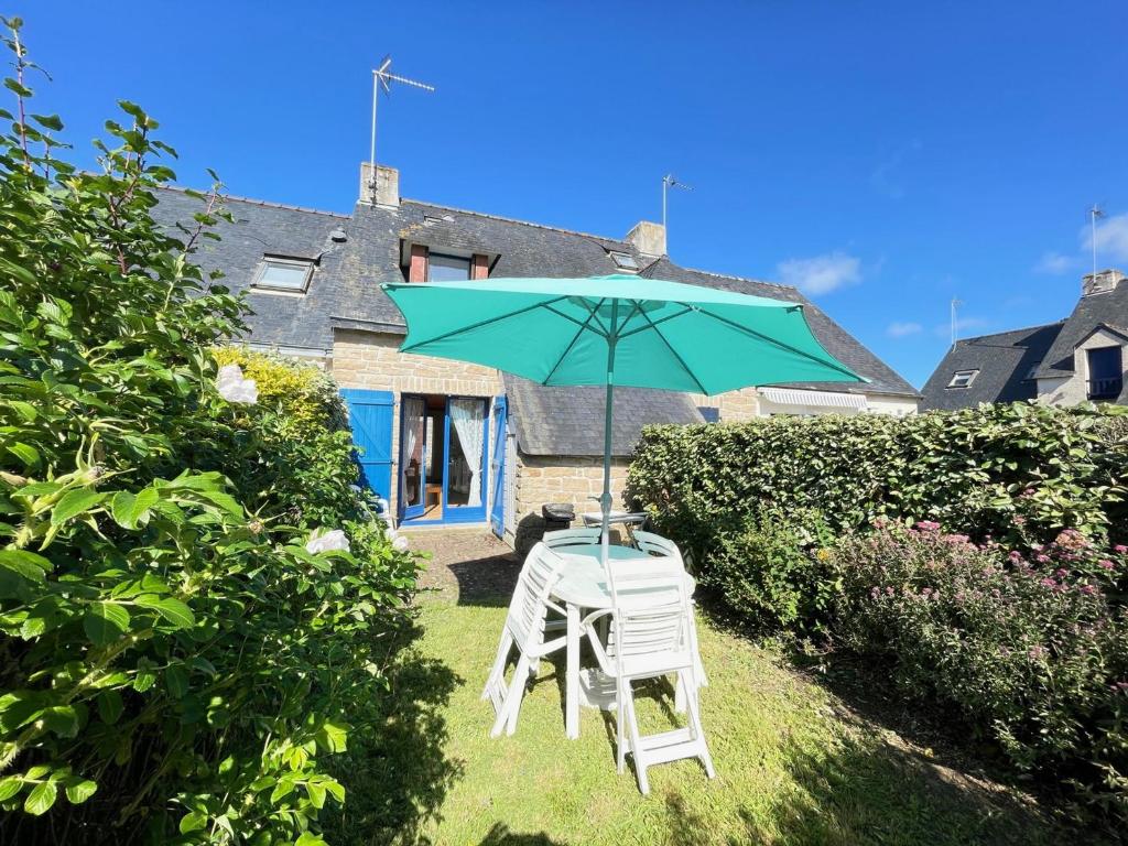 une table et une chaise avec un parasol dans une cour dans l'établissement Maison cosy pour 4 pers., à 250 m de la plage St-Jacques, Sarzeau - FR-1-639-31, à Sarzeau
