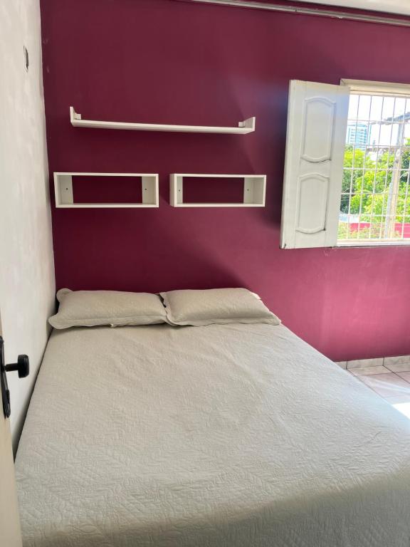 a bed in a bedroom with a purple wall at Quarto em apartamento compartilhado in Teresina