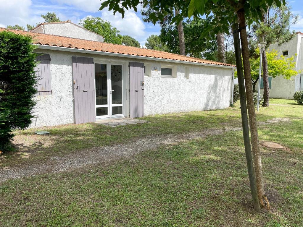 un bâtiment blanc avec des portes et une cour dans l'établissement Villa rénovée 4 pièces 80m² avec patio privé et accès plage - La Palmyre - FR-1-705-71, aux Mathes