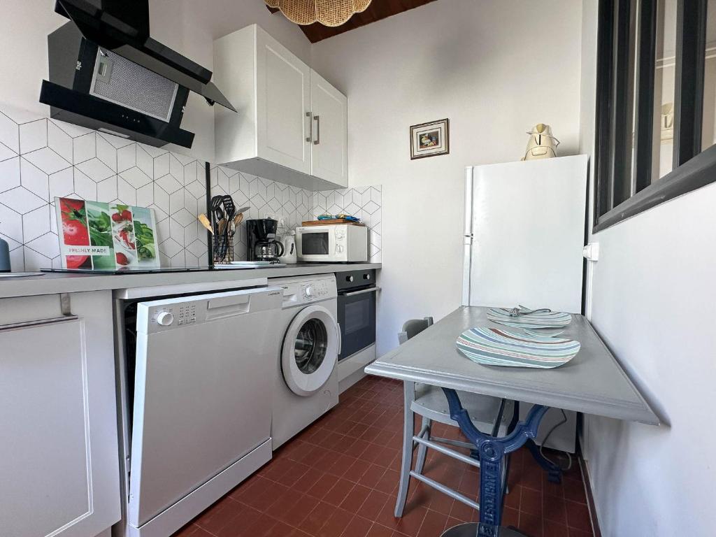 une cuisine avec une machine à laver et une table dans l'établissement Maison de vacances rénovée à La Palmyre - 2 chambres, proche mer et commerces, patio privé. - FR-1-705-72, aux Mathes