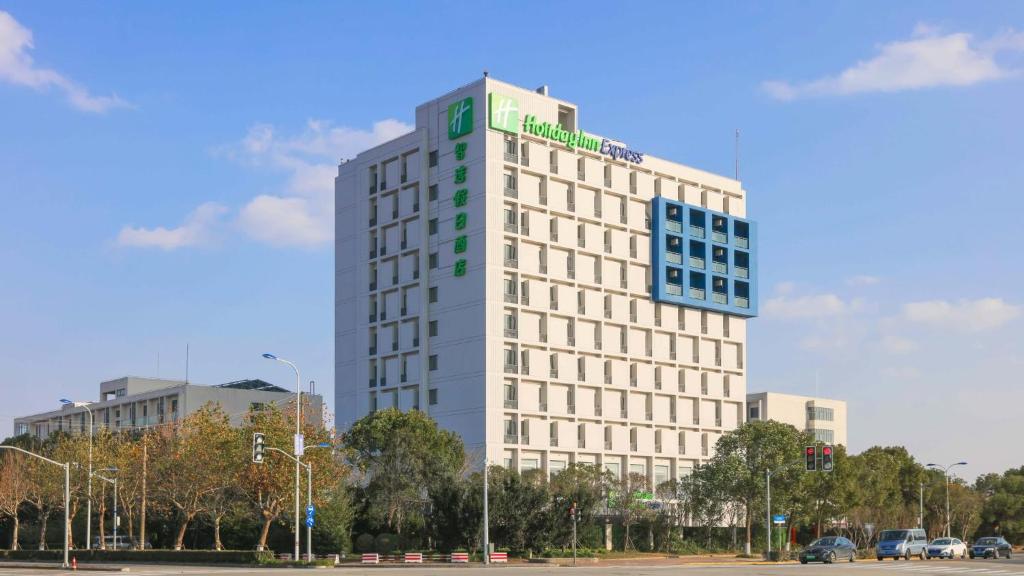 a tall white building with a green sign on it at Holiday Inn Express Shanghai Pudong Airport by IHG in Shanghai