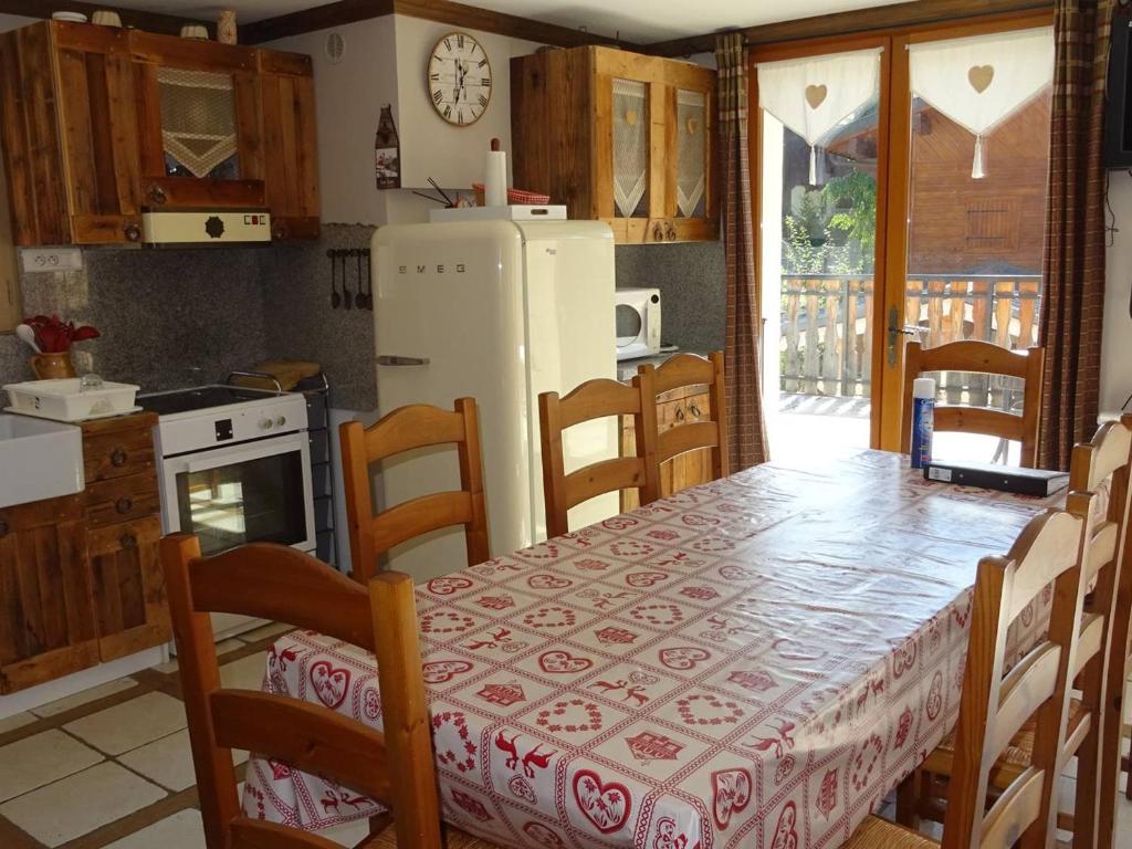une cuisine avec une table, des chaises et un réfrigérateur dans l'établissement Location Les Gets : Spacieux 4 pièces pour 9 pers, proche centre, parking privé, terrasse ensoleillée - FR-1-802-33, aux Gets