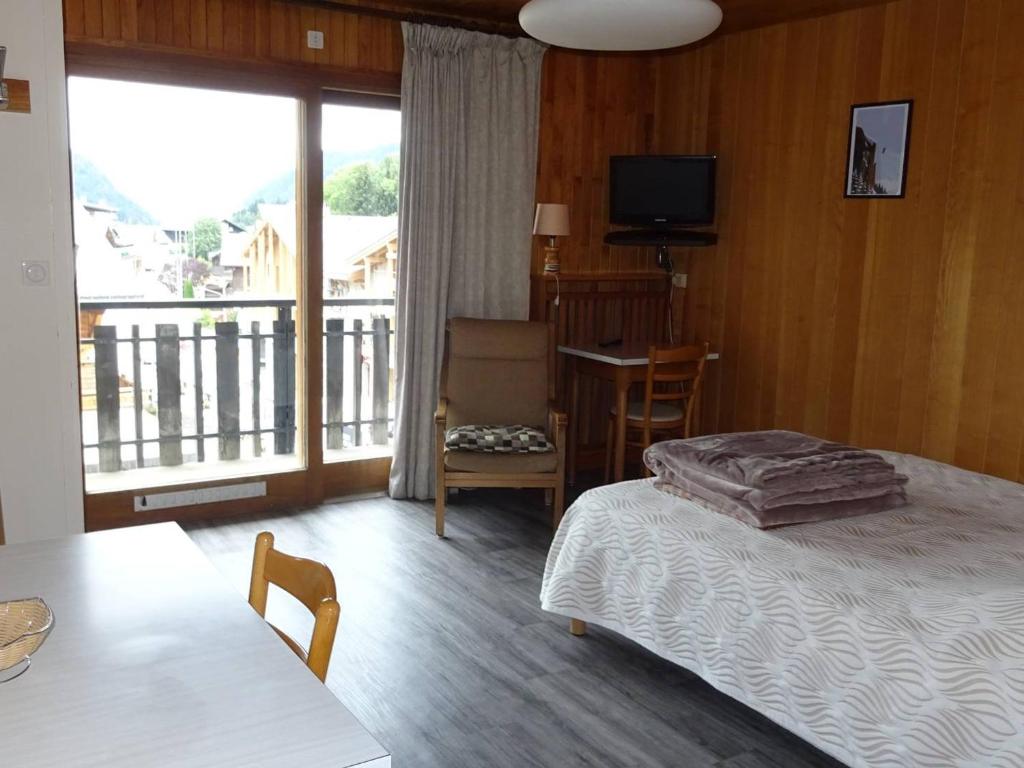 - une chambre avec un lit et un balcon avec une télévision dans l'établissement Studio central Les Gets - 2 pers - WiFi - Draps/Serv inclus - Proche commerces & remontées - FR-1-802-42, aux Gets