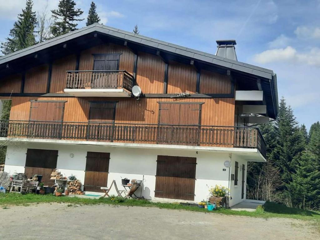 un grand bâtiment avec des portes en bois et un balcon dans l'établissement Les Gets : Duplex 6 pièces pour 12 pers., wifi, garage, proche pistes – Draps et serviettes inclus l’hiver - FR-1-802-9, aux Gets