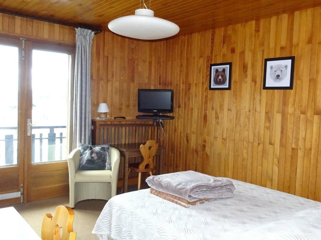 une chambre avec un lit, une télévision et une chaise dans l'établissement Studio aux Gets, 2 pers, centre-ville, Wifi, draps et serviettes inclus - FR-1-802-26, aux Gets