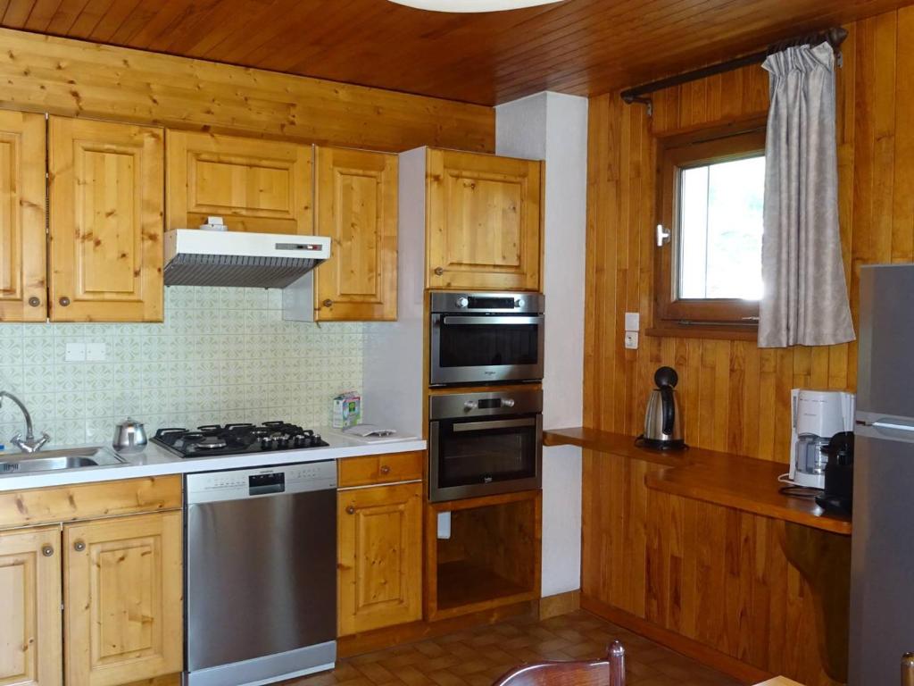 une cuisine avec des armoires en bois et des appareils en acier inoxydable dans l'établissement Appartement 3 Pièces, 6 Pers, Centre des Gets, WiFi, Draps Inclus, Parking Privé - FR-1-802-17, aux Gets
