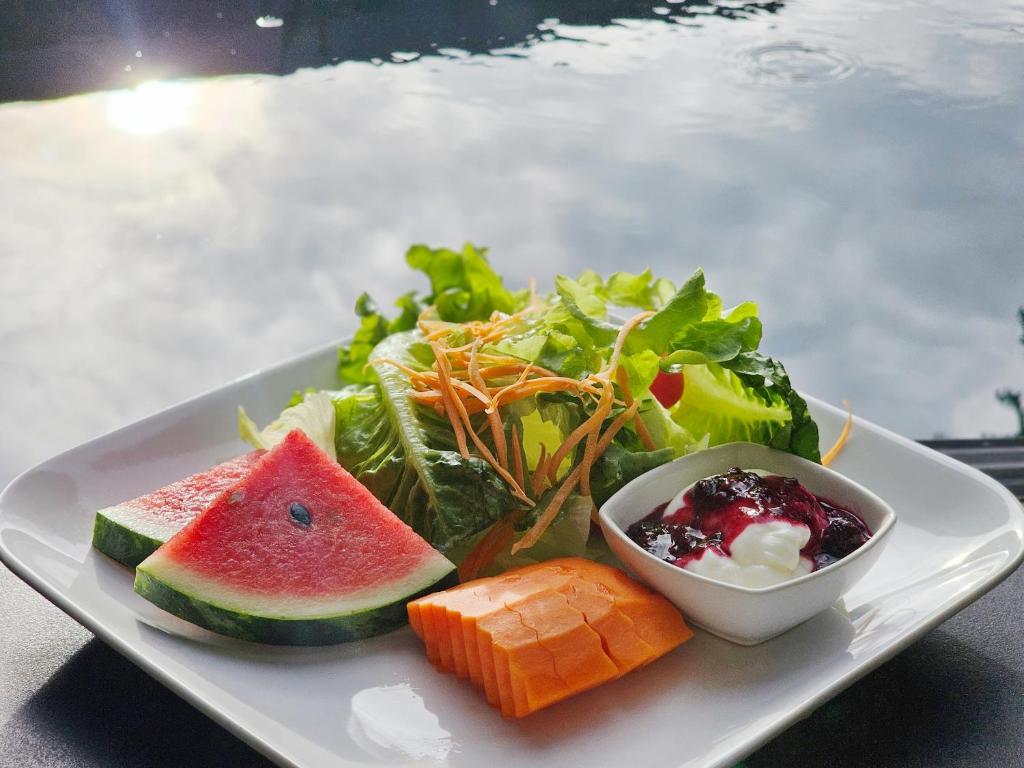 A fresh breakfast plate with salad, watermelon, papaya and berry-topped yogurt.