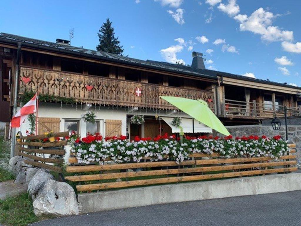 un bâtiment avec des fleurs et un parasol devant lui dans l'établissement Appartement rénové 2 pièces pour 4 personnes aux Gets, proche pistes, parking et WiFi inclus - FR-1-802-91, aux Gets