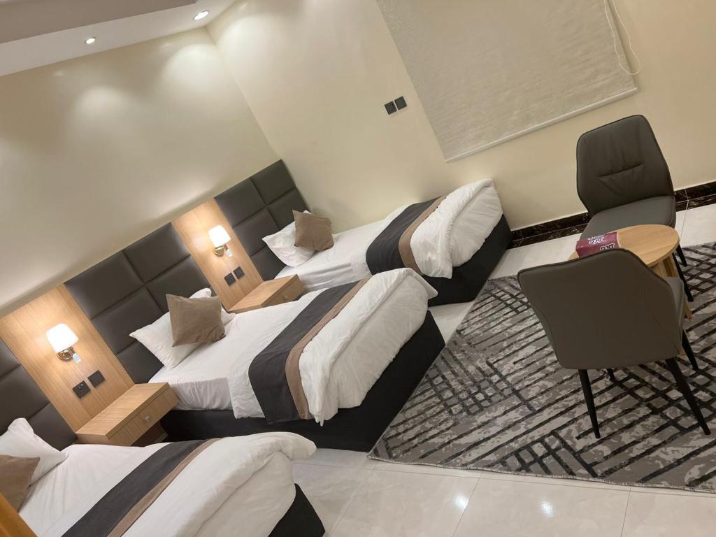 a hotel room with two beds and a chair at مسكن الراقي in Khamis Mushayt