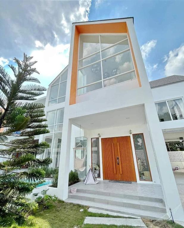 a white house with a wooden door and a palm tree at Luxury Pool Villa 99 in Ban Bang Krang